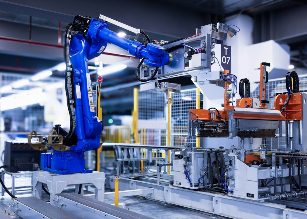 Niebieski robot przemysłowy przy stanowisku montażowym